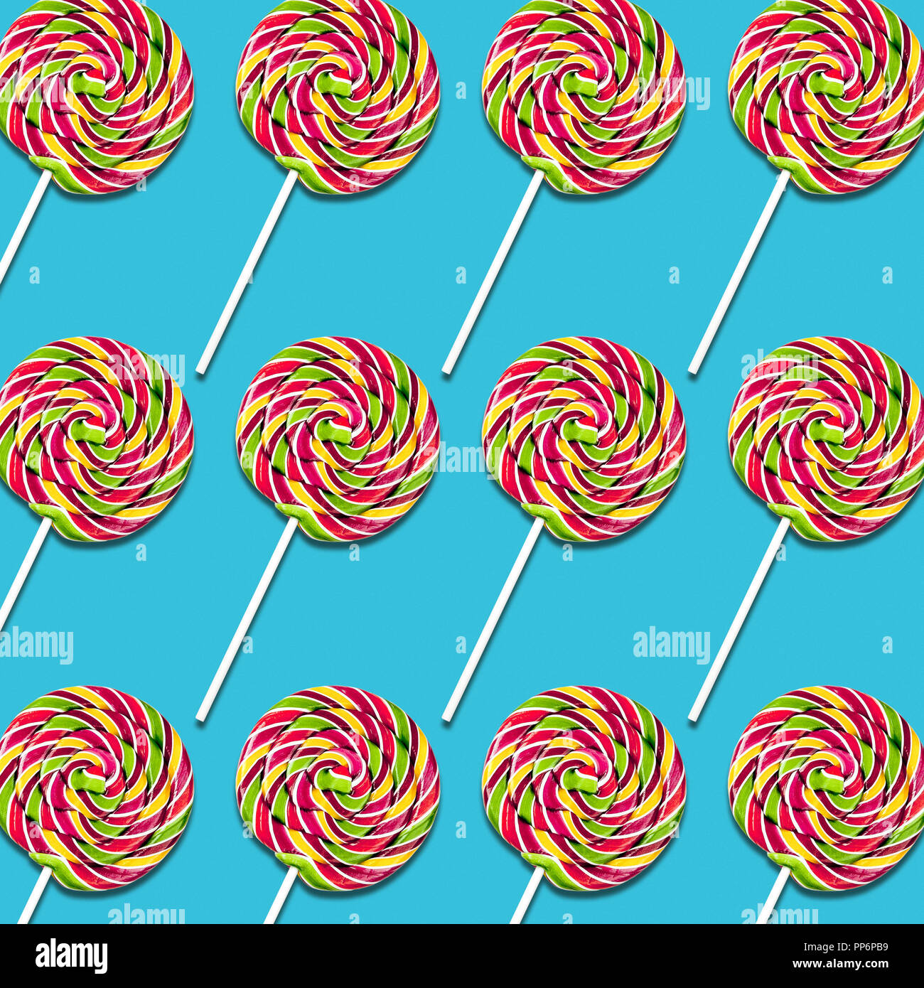 Disposizione simmetrica dei lecca-lecca caramelle su sfondo turchese, colorato sweet food texture Foto Stock