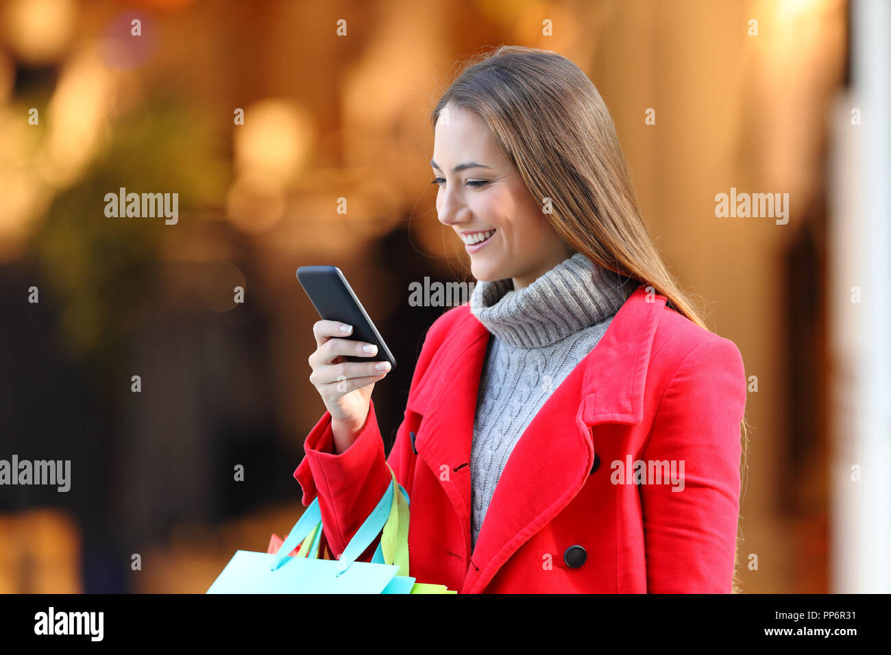 Felice shopping shopper e utilizzando un telefono intelligente in un centro commerciale di inverno Foto Stock