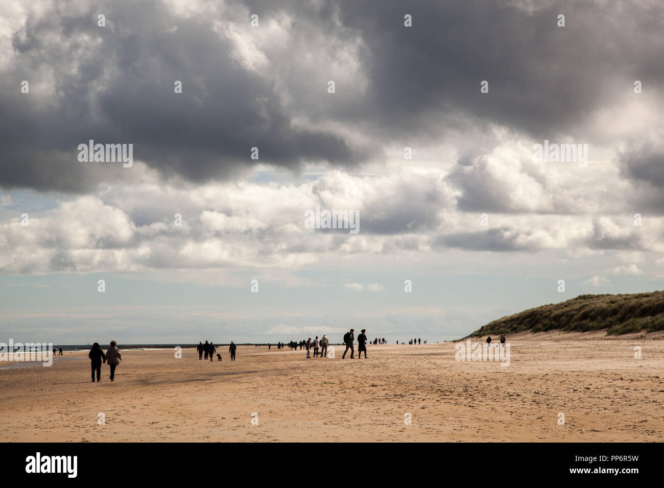 I popoli a piedi lungo la spiaggia di sabbia a Bamburgh Northumberland England Regno Unito Foto Stock