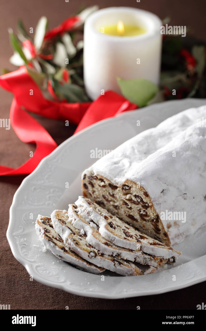 Il Natale lo Stollen con uvetta contro la ghirlanda di Natale e candela Foto Stock