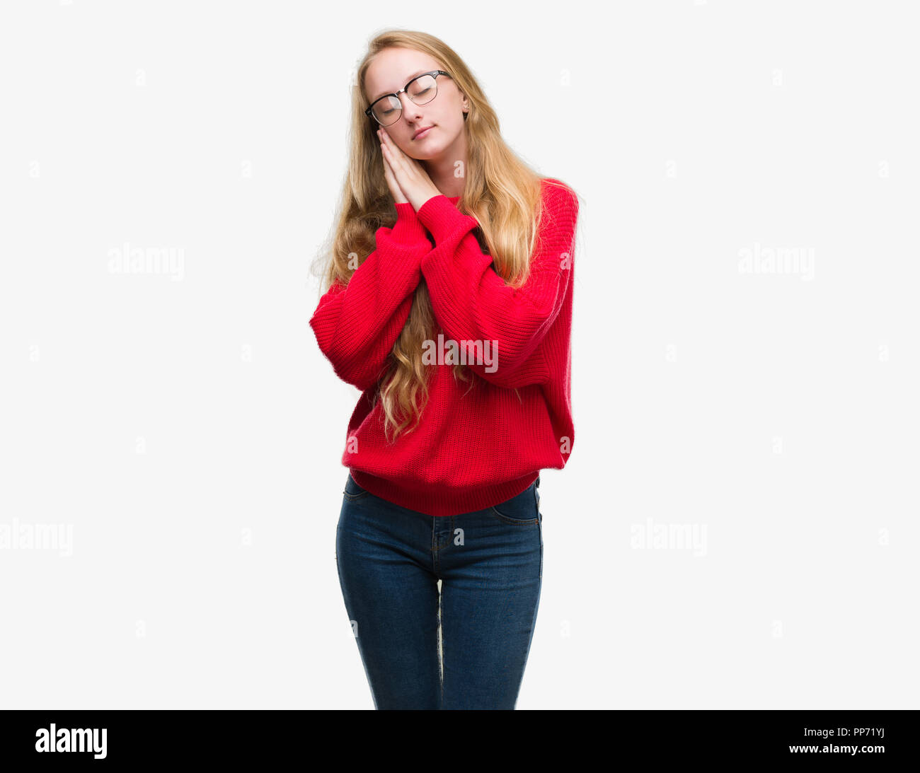Adolescente bionda donna che indossa un maglione rosso dormire stanchi di  sognare e in posa con le mani insieme mentre sorridente con gli occhi  chiusi Foto stock - Alamy