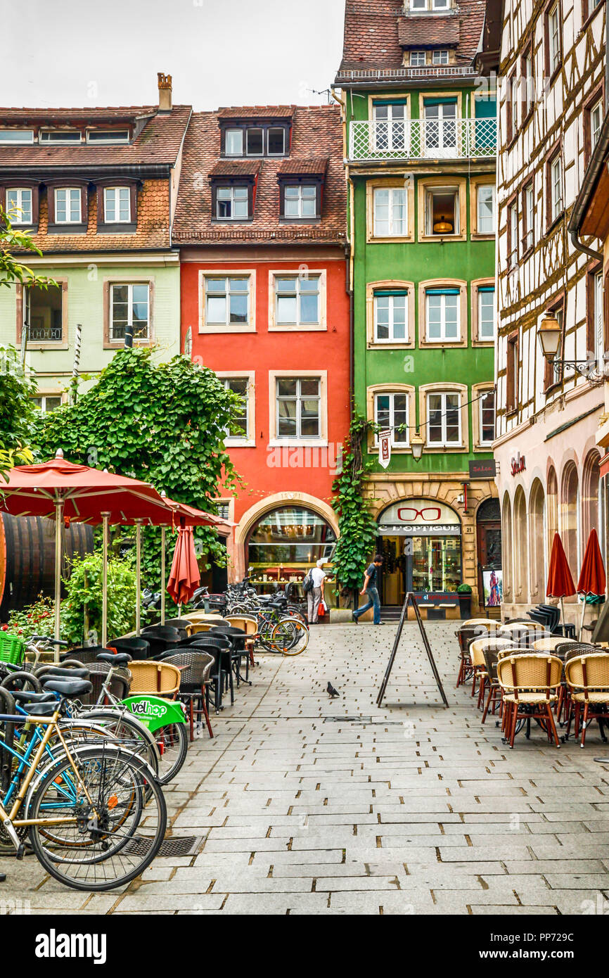Bello e colorato tradizionali edifici francese con ristoranti che offrono pasti all'aperto tavoli e ombrelloni a Strasburgo Francia Foto Stock