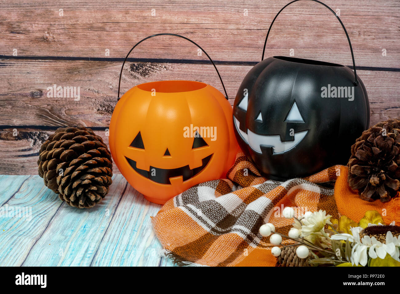 Accogliente Halloween concetto autunno sfondo con zucca jackolantern benne, orange plaid Coperte, pigne e fiori su uno sfondo di legno Foto Stock
