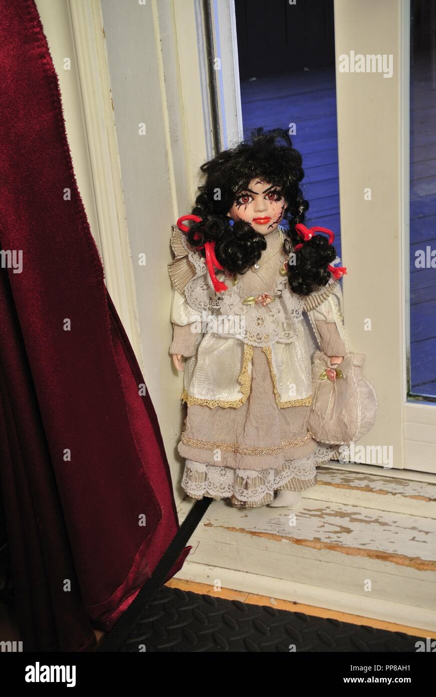 Un creepy porcellana antica bambola con lunghi capelli neri e un pauroso, bella faccia con cicatrici,,vestito in un bianco Vintage dress, venendo voi Halloween Foto Stock