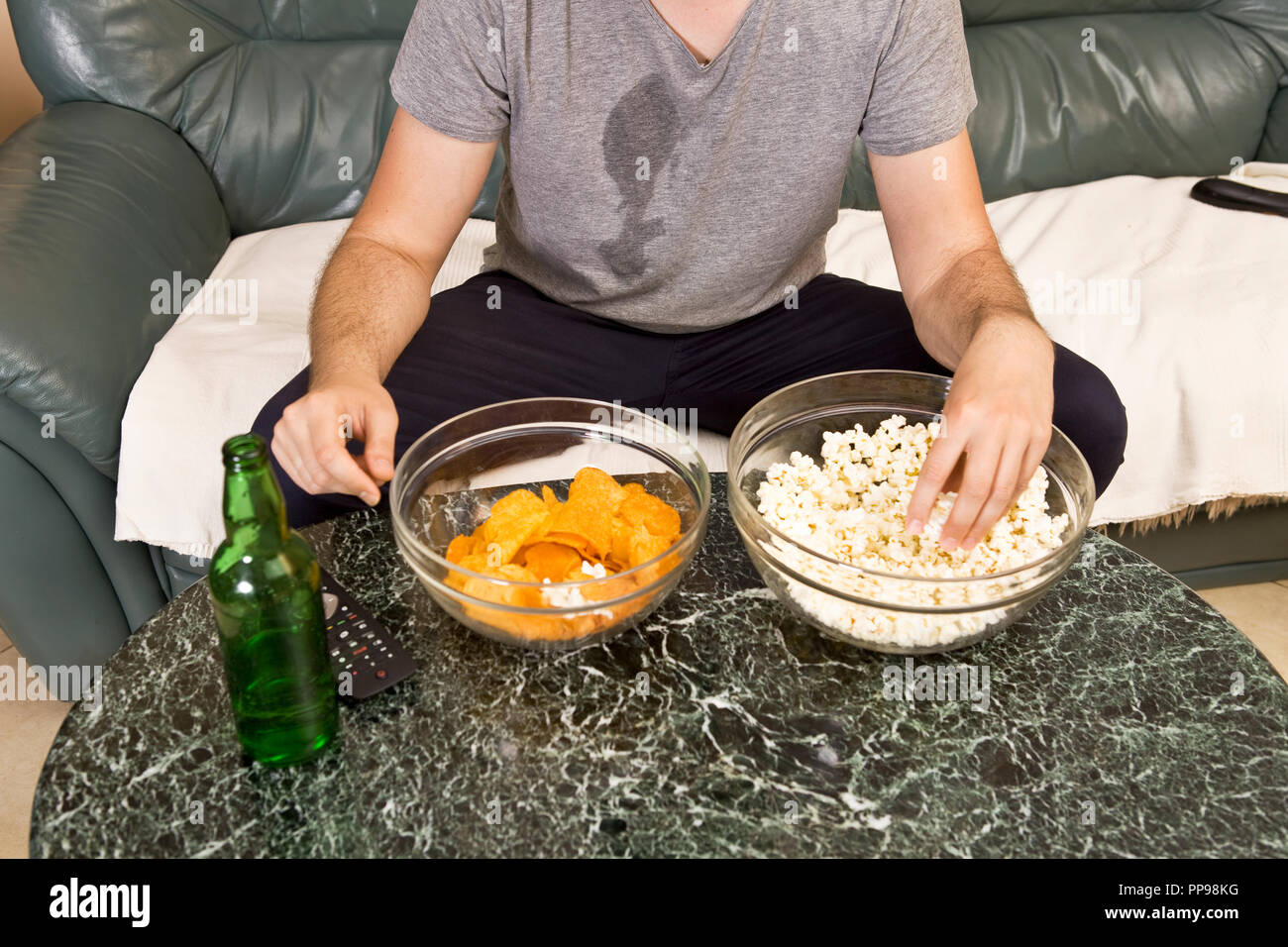 Un giovane uomo guarda la televisione e cambia i canali durante i momenti di relax Foto Stock