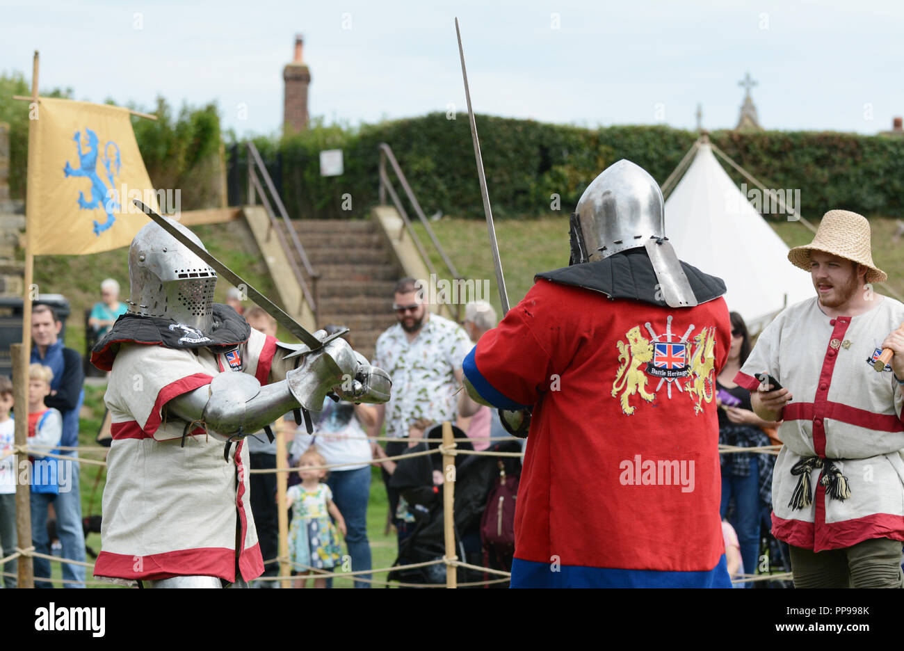 TONBRIDGE, Inghilterra - 9 Settembre 2018: spada lotta tra due combattenti di combattimento vestito in armatura medievale; un marshall in un St Georges Cross ti tabard Foto Stock