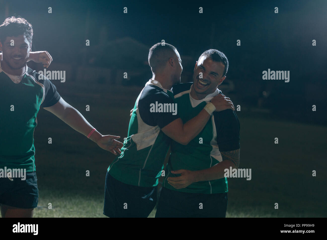 gli sportivi in uniforme si abbracciano e sorridono dopo aver vinto una partita di rugby. giocatori di rugby che festeggiano e festeggiano la vittoria di un campionato. Foto Stock