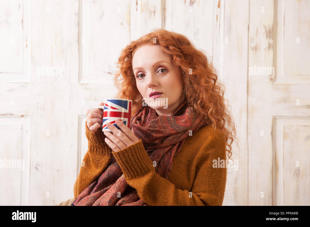 Donna che mantiene unione jack cup, cercando in questione Foto Stock