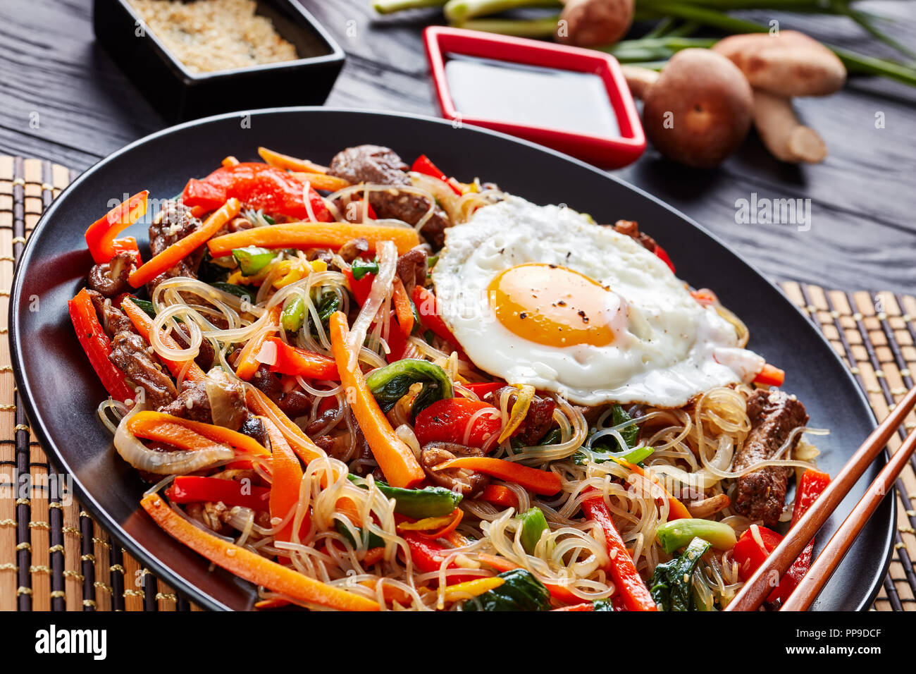 Japchae piatto coreano: vetro tagliatelle con stir peperone fritto, carote, spinaci, la cipolla, l'uovo, aglio, funghi shiitake e lunghe strisce di carne fritti, Dre Foto Stock