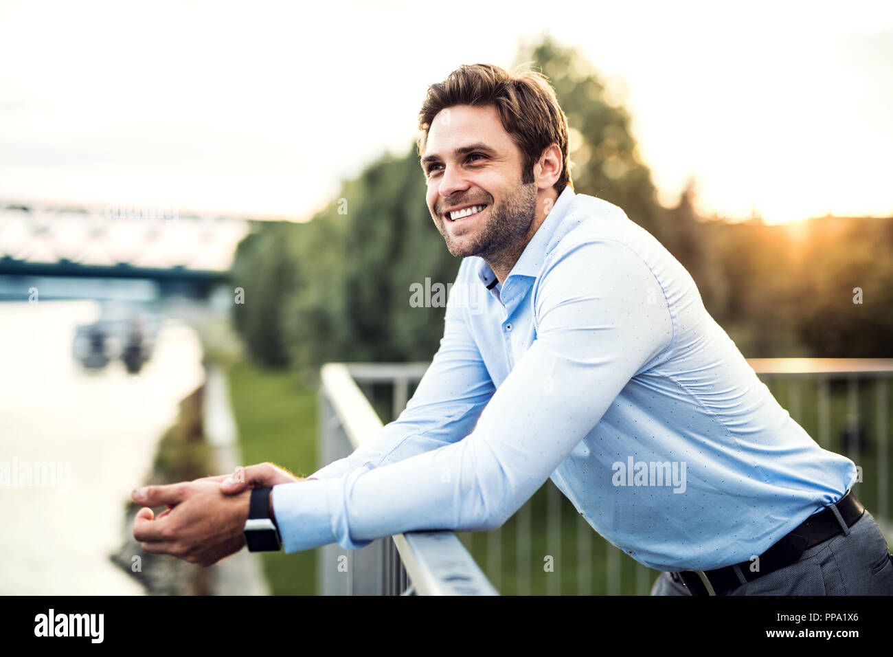 Un giovane imprenditore in piedi su un ponte, poggiando su una ringhiera. Foto Stock
