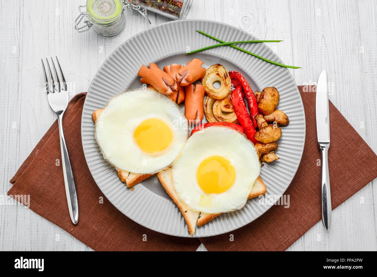 Impostare per prima colazione uova fritte, verdure grigliate, salsicce. Il pane su una tavola di legno. Foto Stock