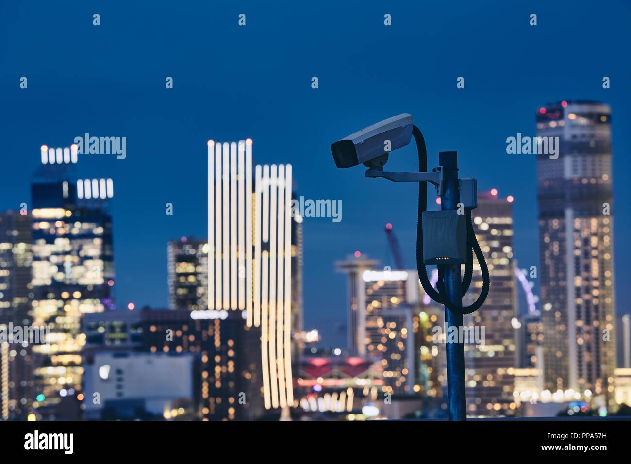 Videocamera di sicurezza contro illuminato urban skyline di notte. Concetto di sorveglianza, la protezione e la sicurezza. Foto Stock