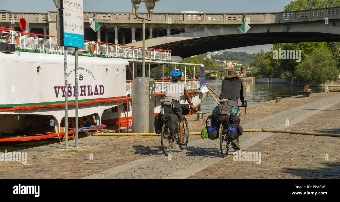 Due persone in bicicletta su un sentiero lungo il fiume Vltava nel centro di Praga Foto Stock