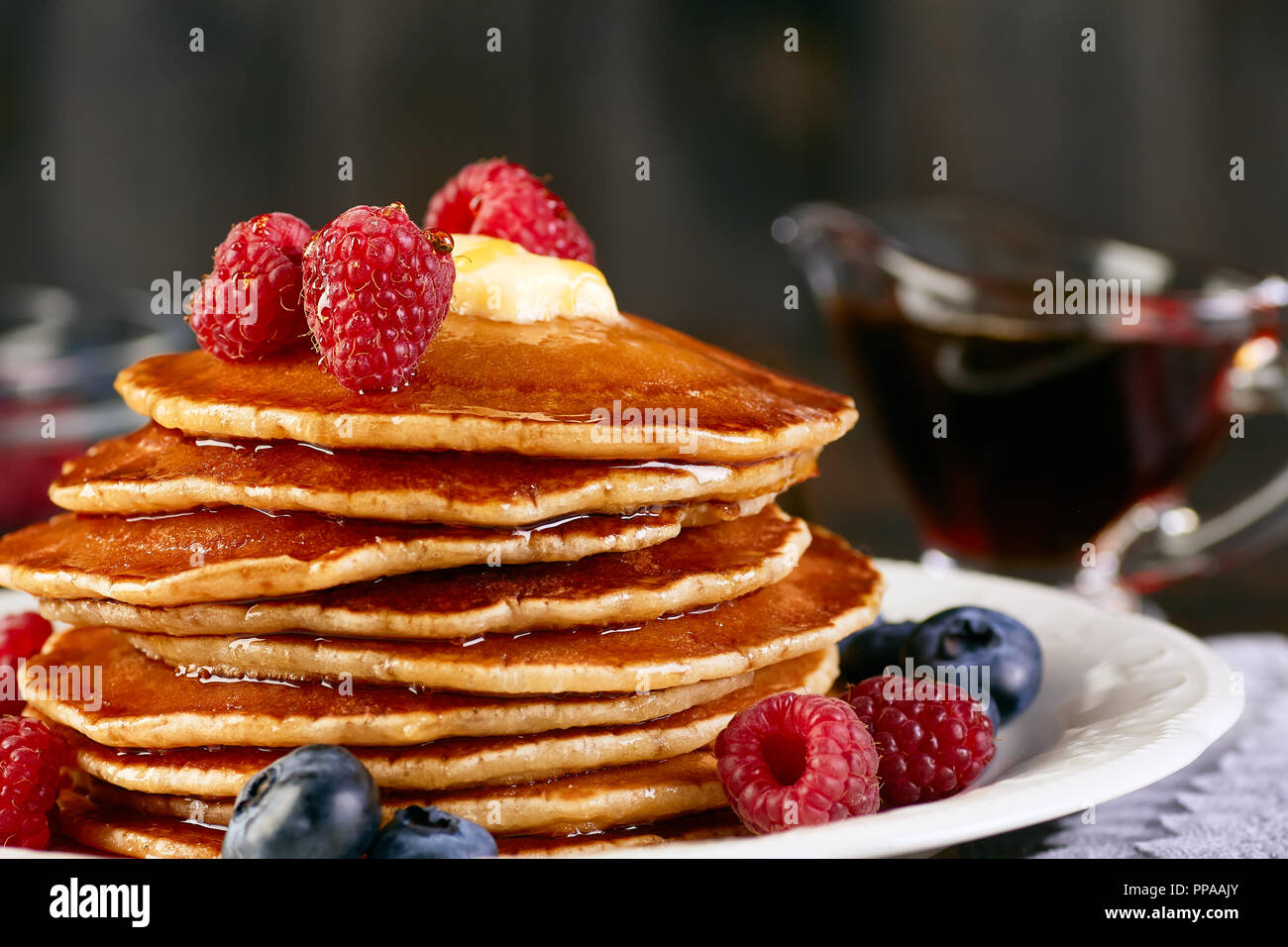 Pila di pancake con bacche e sciroppo d'acero Foto Stock