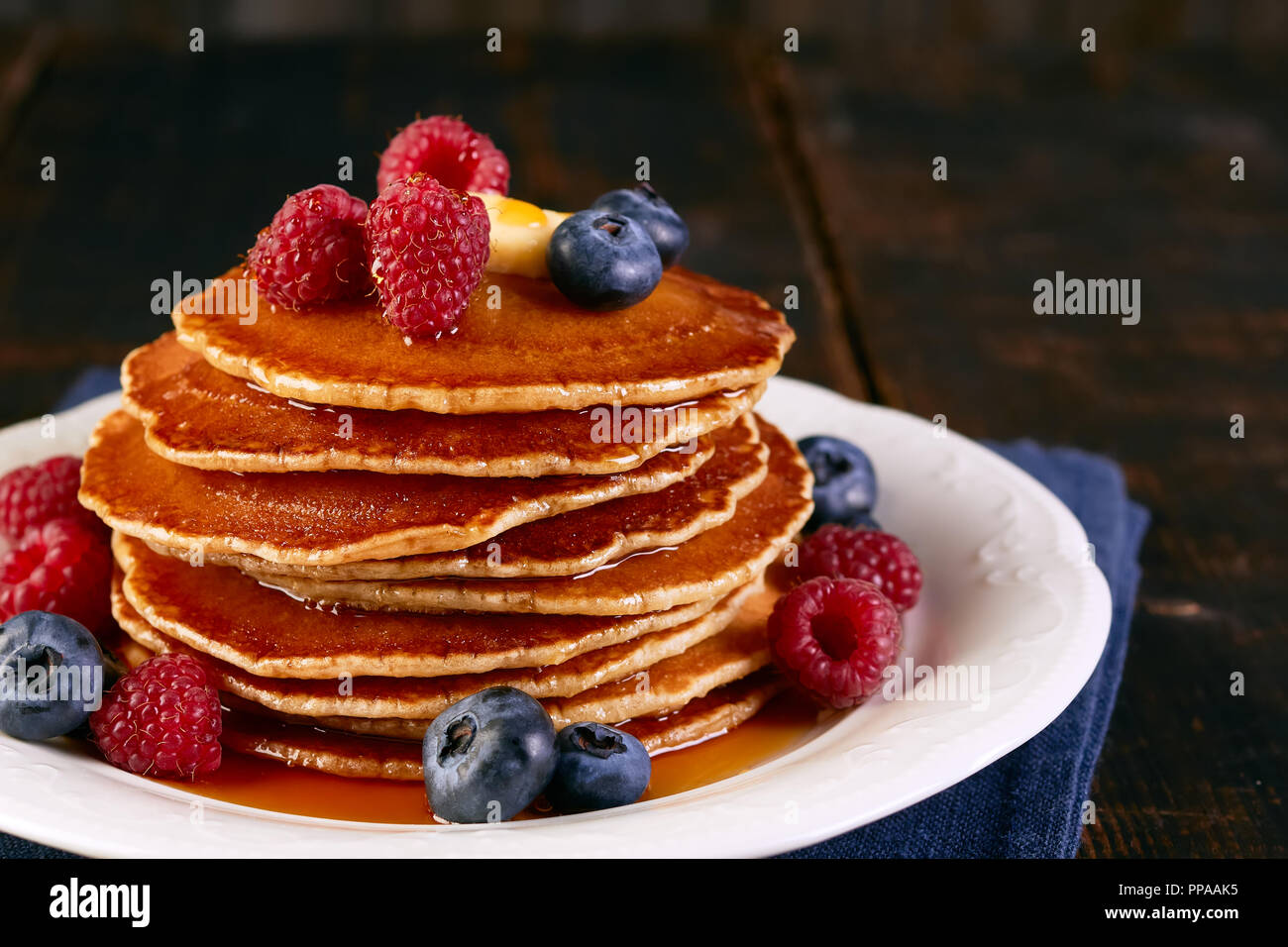 Pila di pancake con bacche e sciroppo d'acero sul piatto Foto Stock