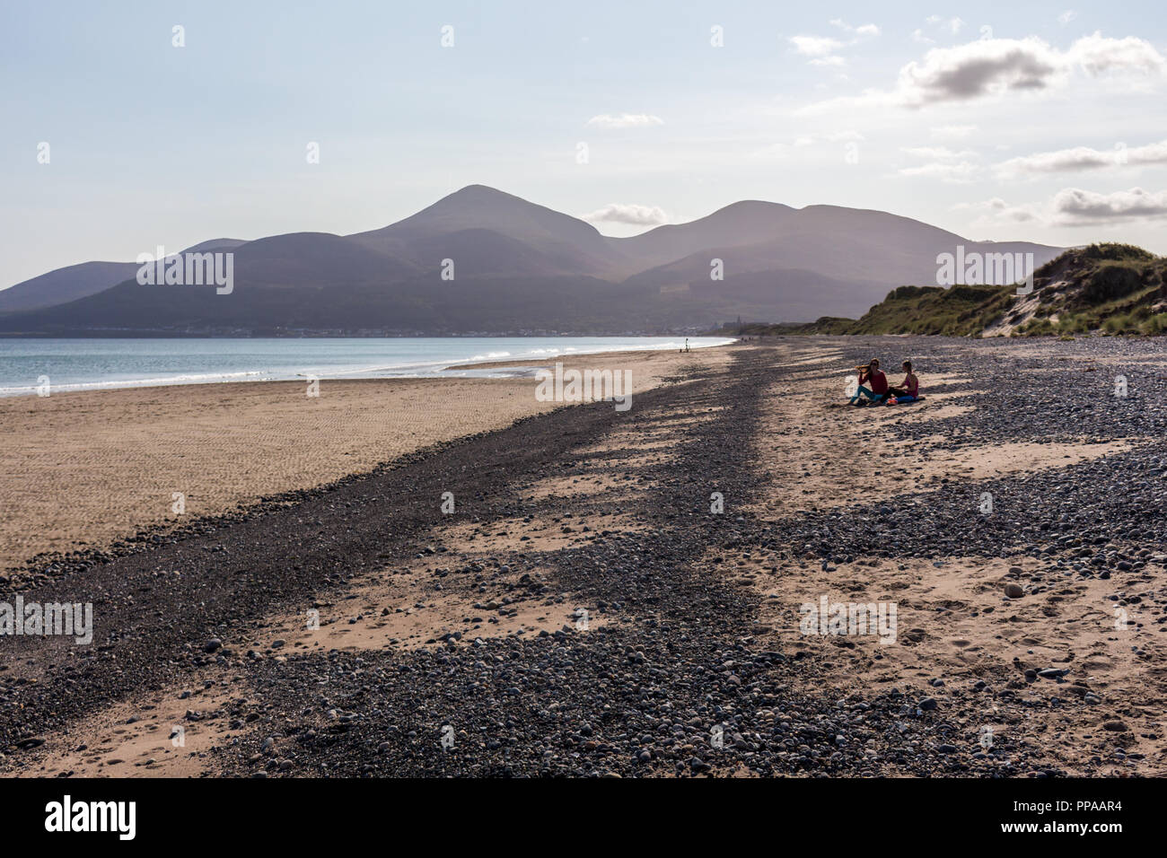 La gente seduta relax su una spiaggia tranquilla con vista di Mourne Mountains. Murlough beach, Newcastle, County Down, N.Irlanda. Foto Stock