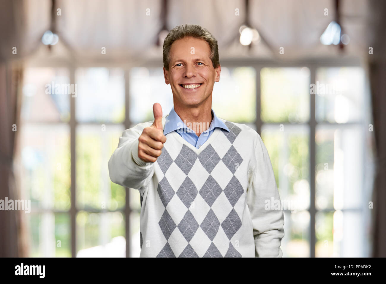 Bel uomo maturo gesticolando pollice in alto. Foto Stock