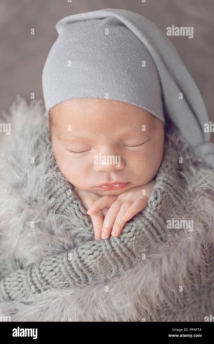 Neonato ragazza avvolto in grigio con le piume, dormendo Foto Stock