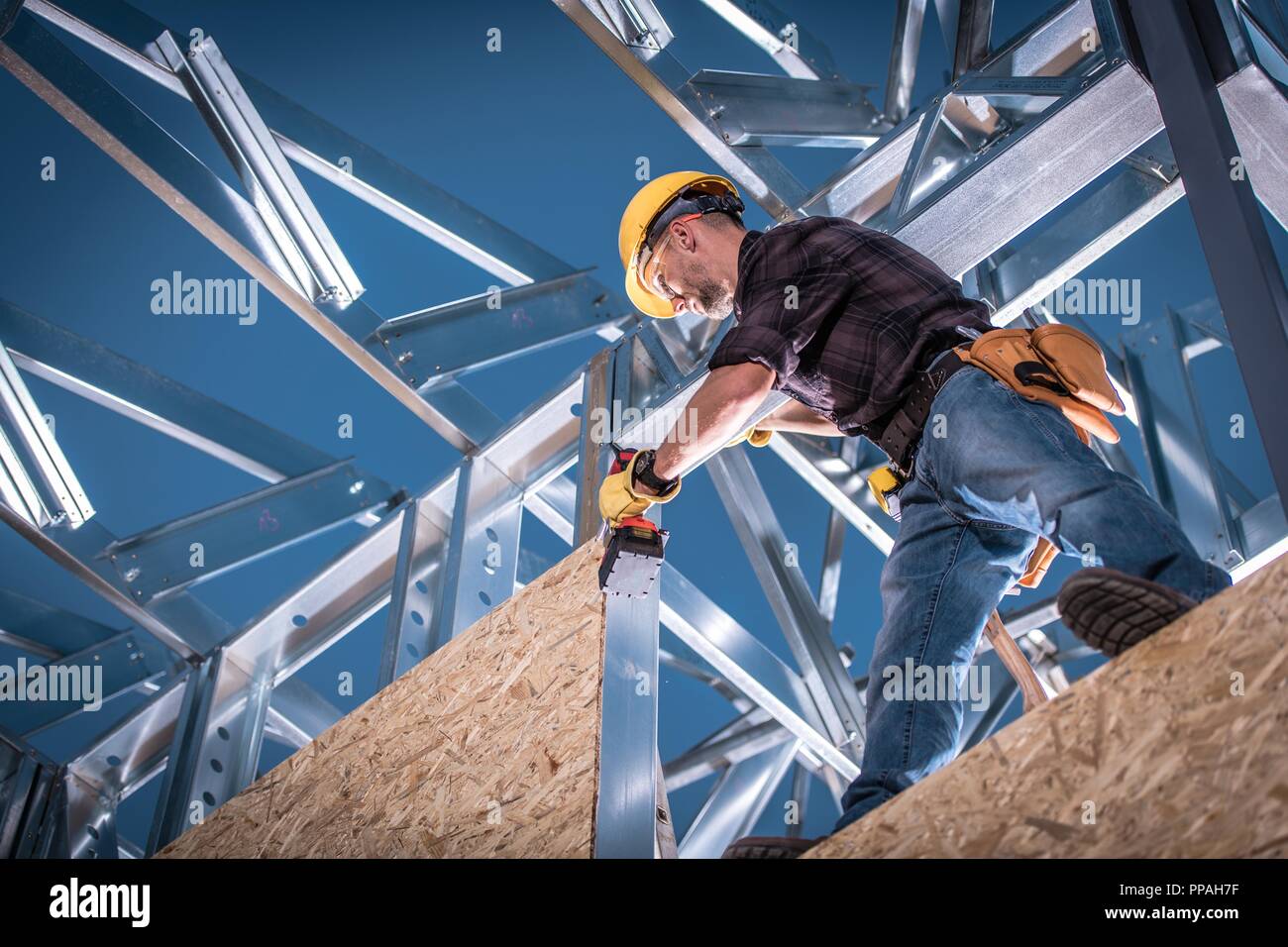 Casa in acciaio costruttore lavoratore. Lavoratore caucasici con strumento di potere sul telaio di costruzione. Foto Stock