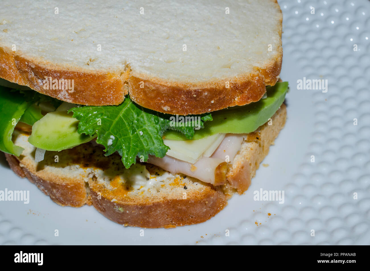 Home pane cotto affettato per creare sandwich riempito con la Turchia, avocado, cresciuto in casa pepe verde e Kale. Nutriente delizioso pranzo o cena. Foto Stock