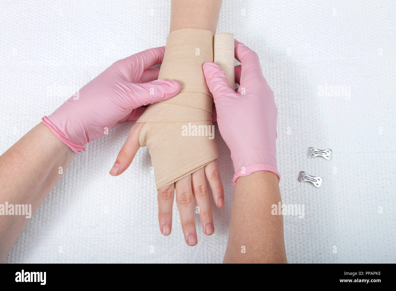 Giovani mani femminili indossando guanti di rosa involucro elastico  bendaggio ace sul giovane mano e polso. Trattamento medico Foto stock -  Alamy