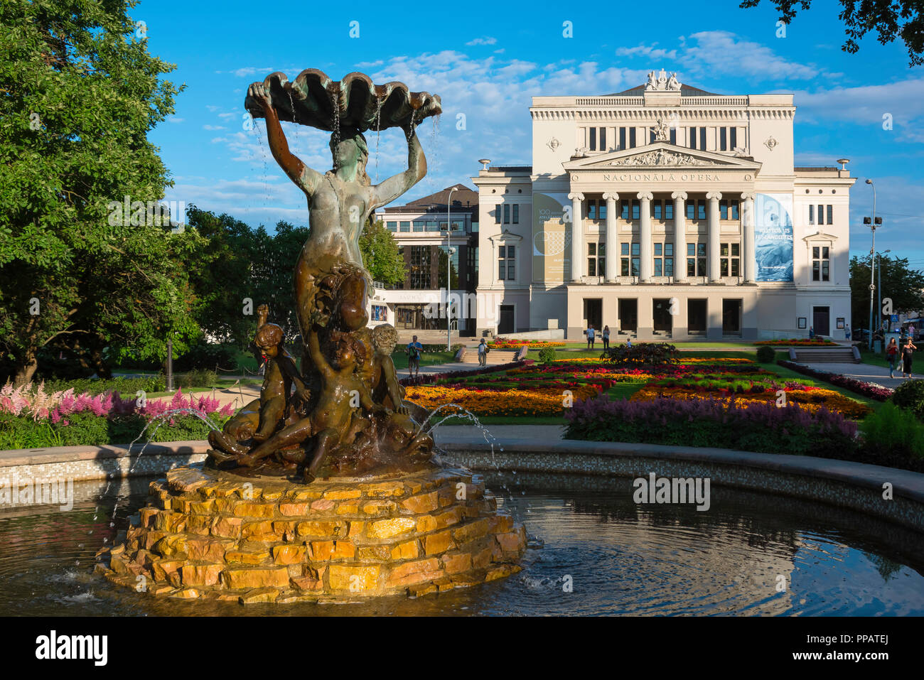 Teatro dell'Opera di Riga, visualizzare passato la fontana nel Strulaka parco e giardino verso la facciata neoclassica del Teatro dell'Opera di Riga Edificio, Lettonia. Foto Stock