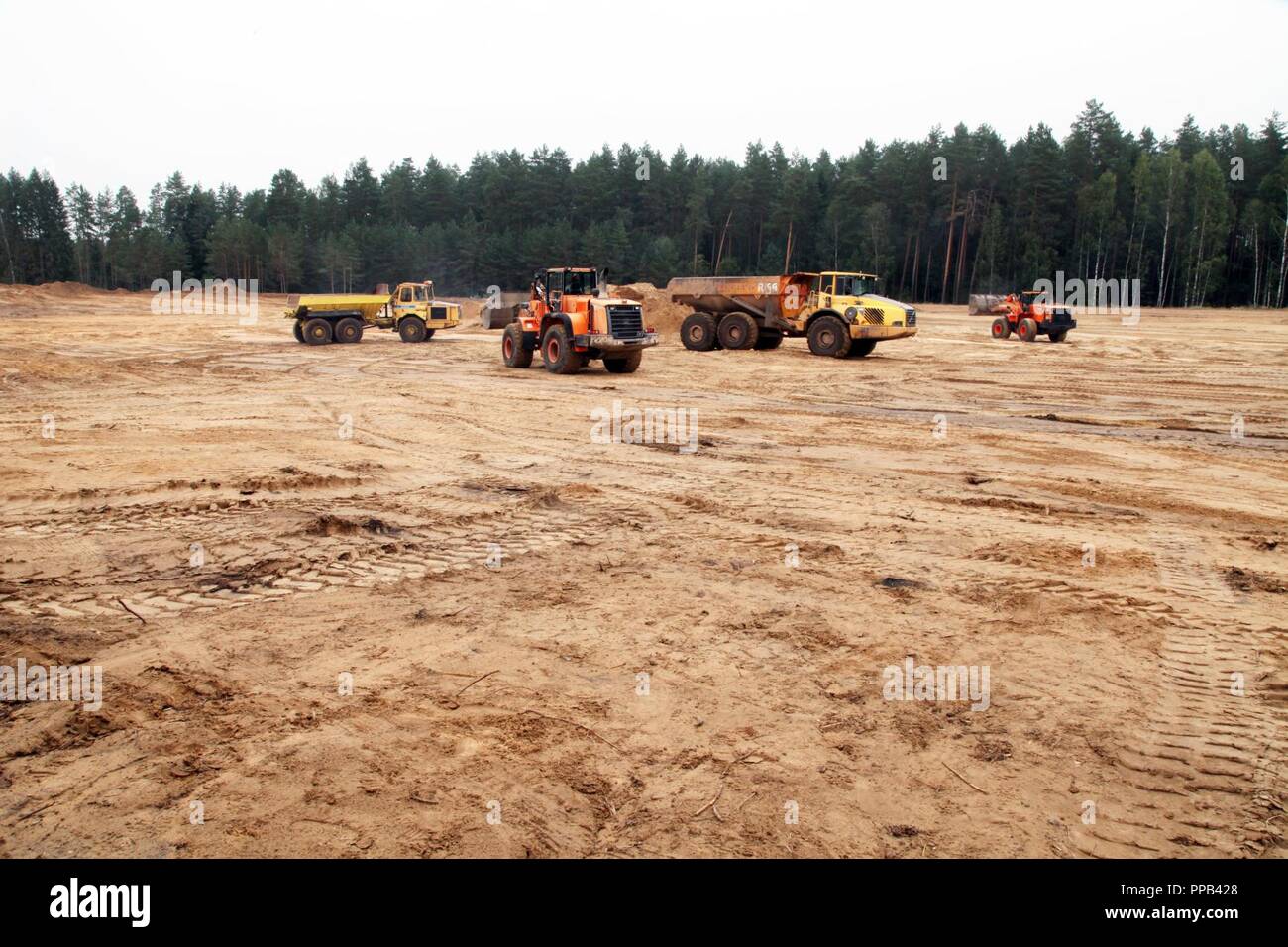 Un esercito di pesanti caricatori frontali di convergere su una roccia/autocarro con cassone ribaltabile del suo riempimento con 5 metri cubi di materiale usato come riempimento. Airman dal 201st rosso squadrone di cavalli, Pennsylvania, implementata per la formazione di costruire un'aria-terra di gamma per essere utilizzato da lituani e le forze della NATO. Questo è il terzo di quattro rotazioni che la convergenza su Kurzu Ruda Air Base, la Lituania per completare questa missione. Foto Stock