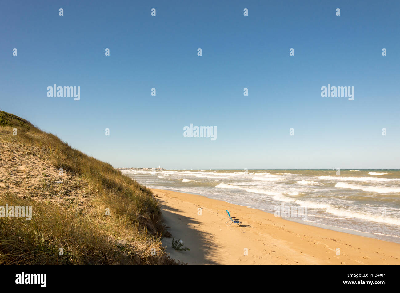 Solitaria sedia verde sulla sabbiosa e ventoso spiagge del mare adriatico Foto Stock