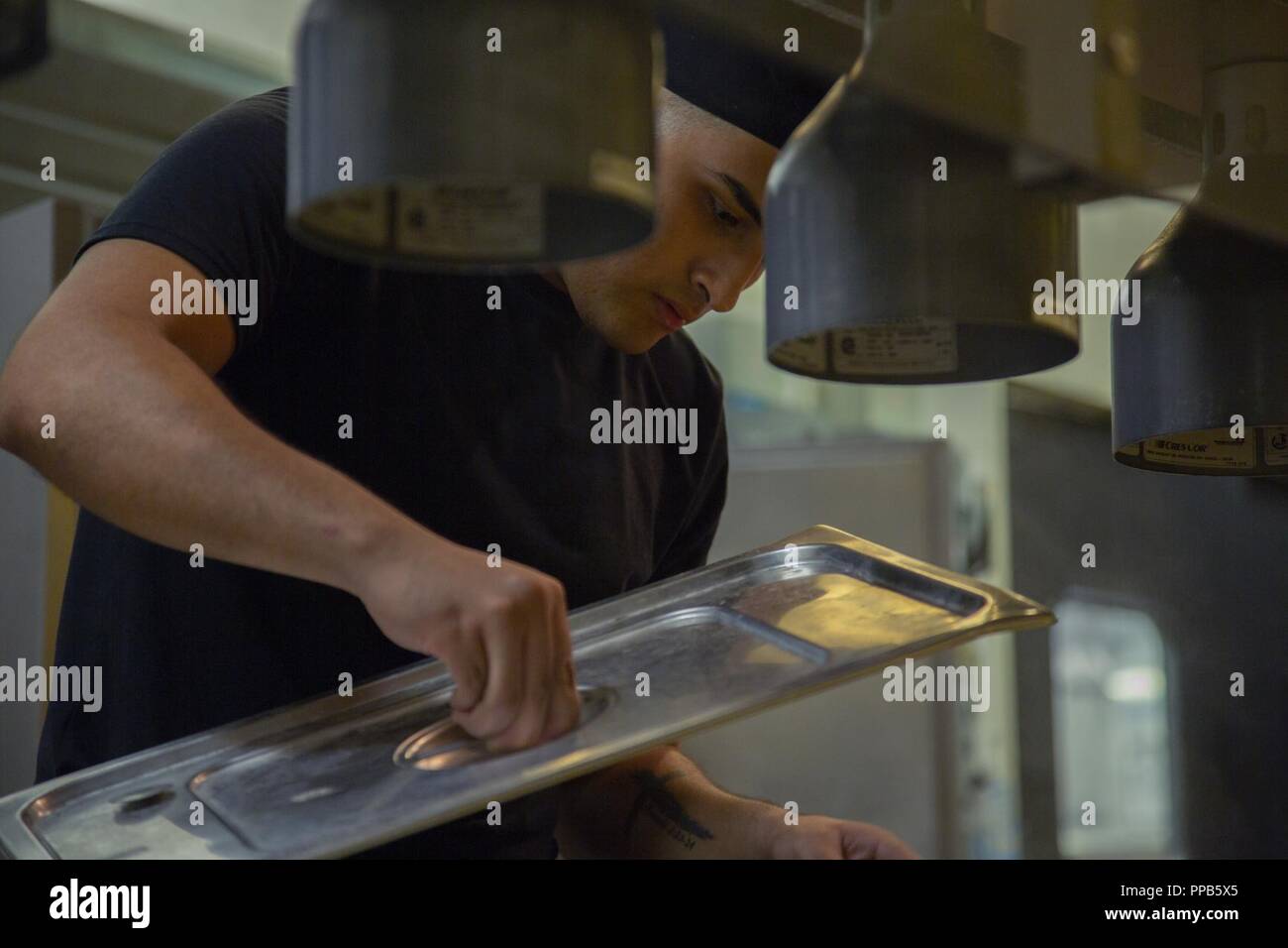 Pfc. Havier Contreras prepara il contatore di cibo in preparazione per il pasto pomeridiano al Camp Kinser Mess Hall di Okinawa, in Giappone, 15 agosto 2018. Il servizio di ristorazione gli specialisti forniscono cibo e servizi di caffetteria per la flotta forze Marine in entrambi i campi e gli ambienti di guarnigione. Contreras, food service specialist con servizio di cucina Azienda, Sede reggimento, 3° Marine Logistics Group, è un nativo di San Antonio, Texas. Foto Stock