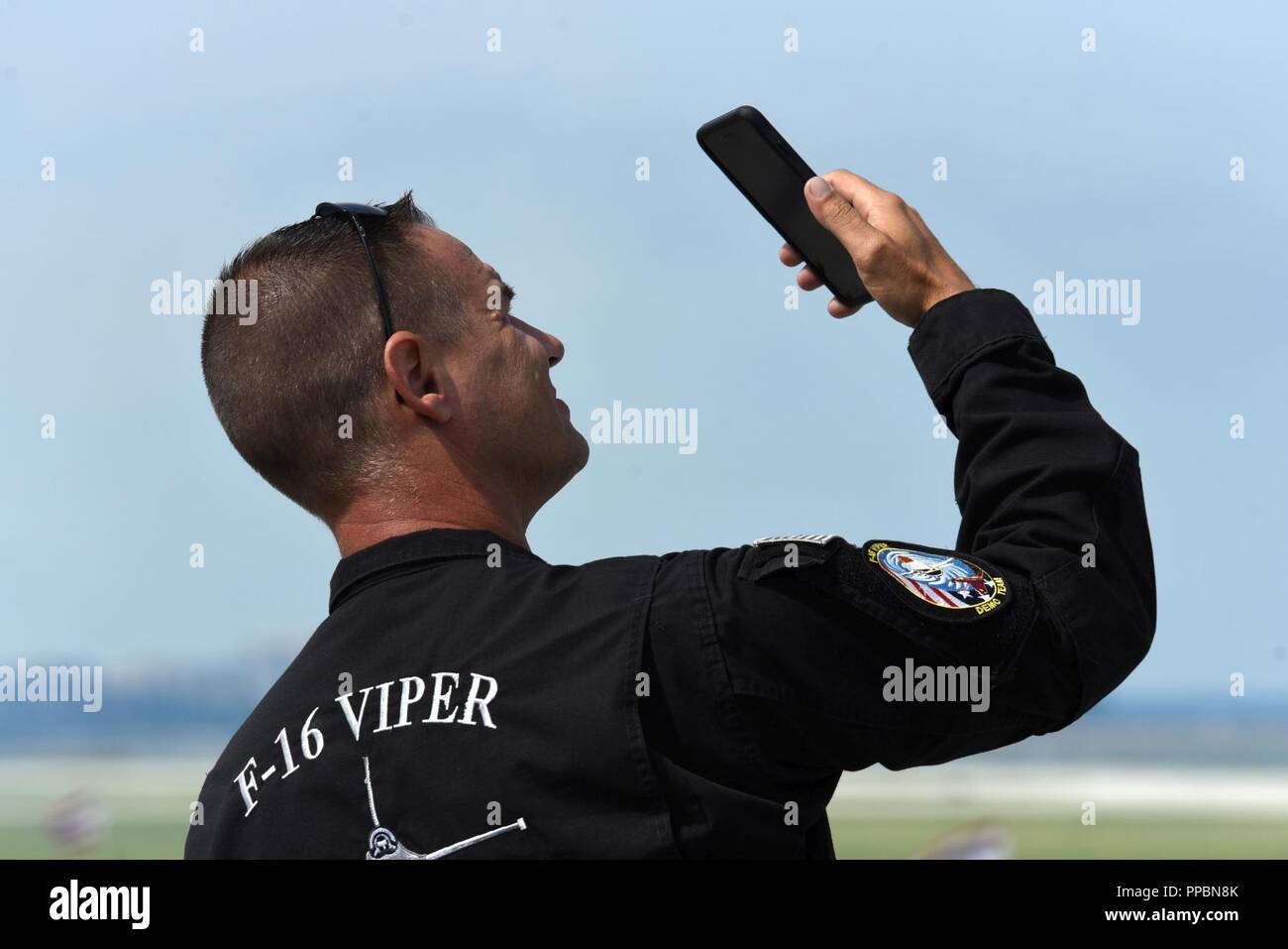 Stati Uniti Air Force Master. Sgt. Chris Schneider, F-16 Viper team di dimostrazione (VDT) sovrintendente, mostra i suoi figli gli aeromobili della pratica per il Cleveland National Air Show durante una chiamata video sull'Aeroporto Burke Lakefront linea di volo a Cleveland, Ohio, 31 Agosto, 2018. Schneider ha sostenuto il suo team durante l'evento da coordinare con spettacolo di amministrazione, fornire una leadership e narrare la dimostrazione del team. Foto Stock