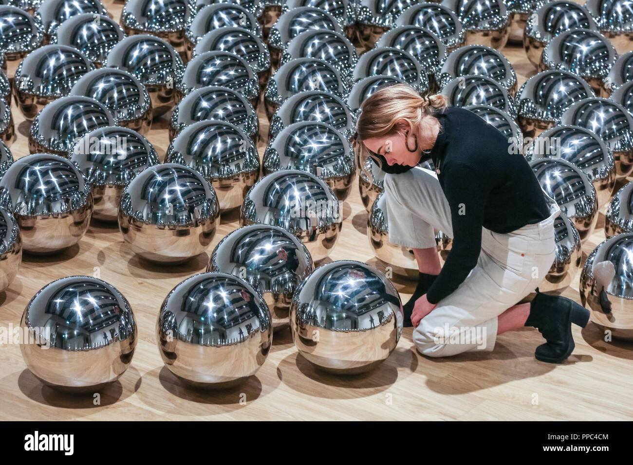 Londra, UK, 25 settembre 2018. Un assistente di galleria pone di Yayoi Kusama del giardino di Narciso con centinaia di sfere in acciaio. Hayward Gallery è di nuovo grande spazio espositivo Shifters dispone di opere d'arte da 20 importanti artisti internazionali che interrompono il visitatore il senso di spazio e di alterare la loro percezione dei loro dintorni. La mostra viene eseguito 26 settembre - 6 gennaio. Credito: Imageplotter News e sport/Alamy Live News Foto Stock