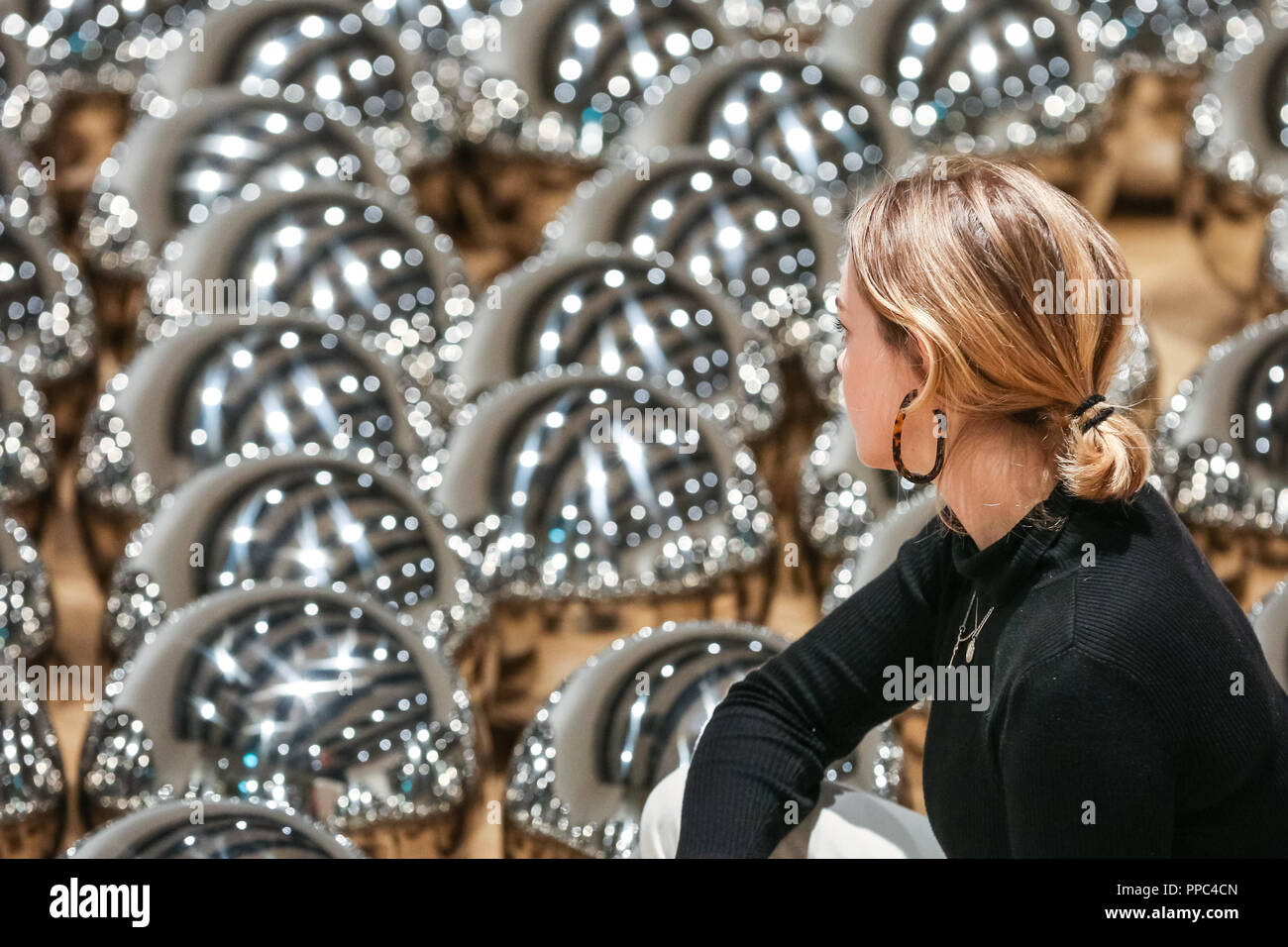 Londra, UK, 25 settembre 2018. Un assistente di galleria pone di Yayoi Kusama del giardino di Narciso con centinaia di sfere in acciaio. Hayward Gallery è di nuovo grande spazio espositivo Shifters dispone di opere d'arte da 20 importanti artisti internazionali che interrompono il visitatore il senso di spazio e di alterare la loro percezione dei loro dintorni. La mostra viene eseguito 26 settembre - 6 gennaio. Credito: Imageplotter News e sport/Alamy Live News Foto Stock