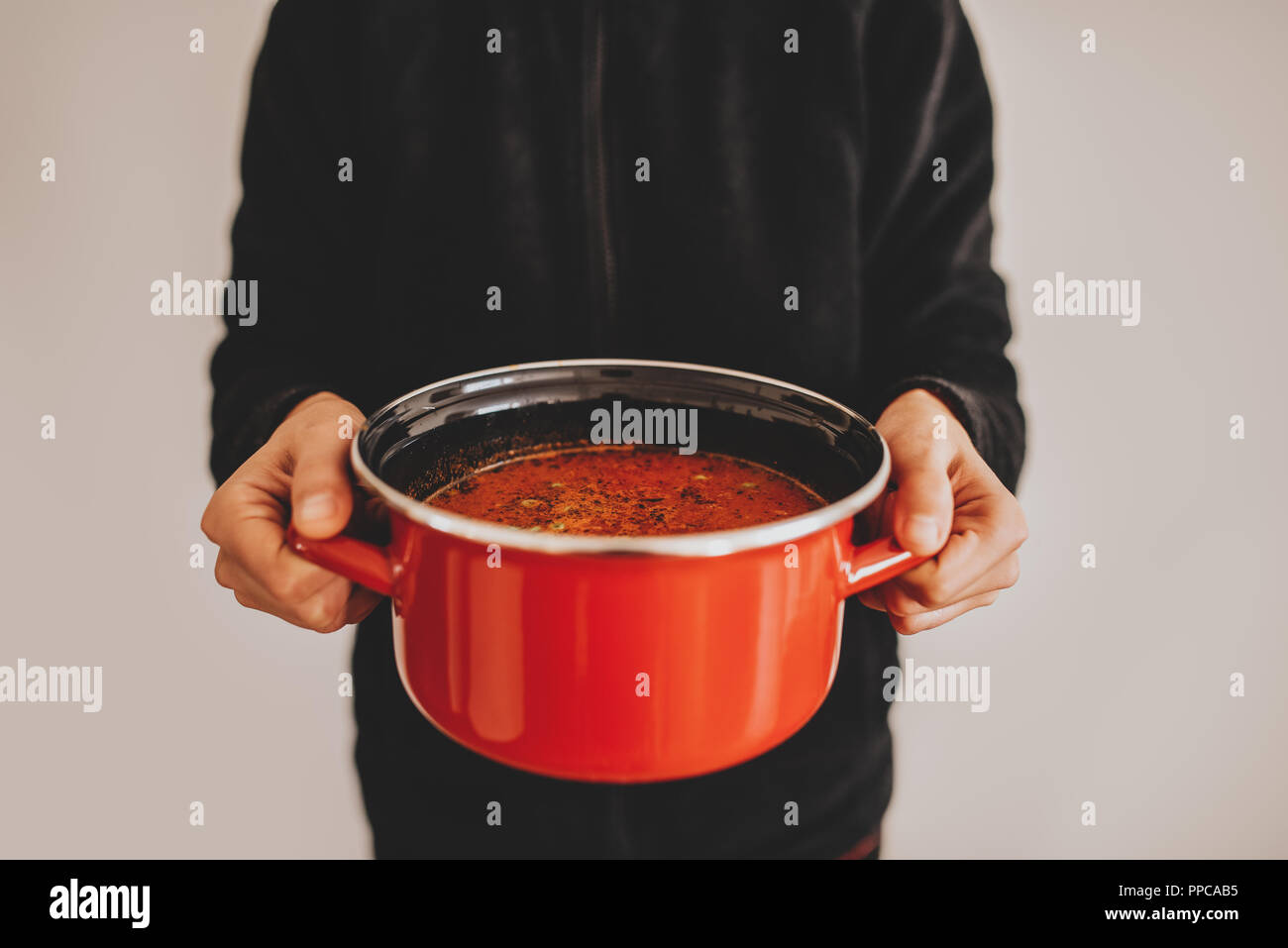 Mani femminili azienda red pot con zuppa di verdure. Cibo sano concetto Foto Stock