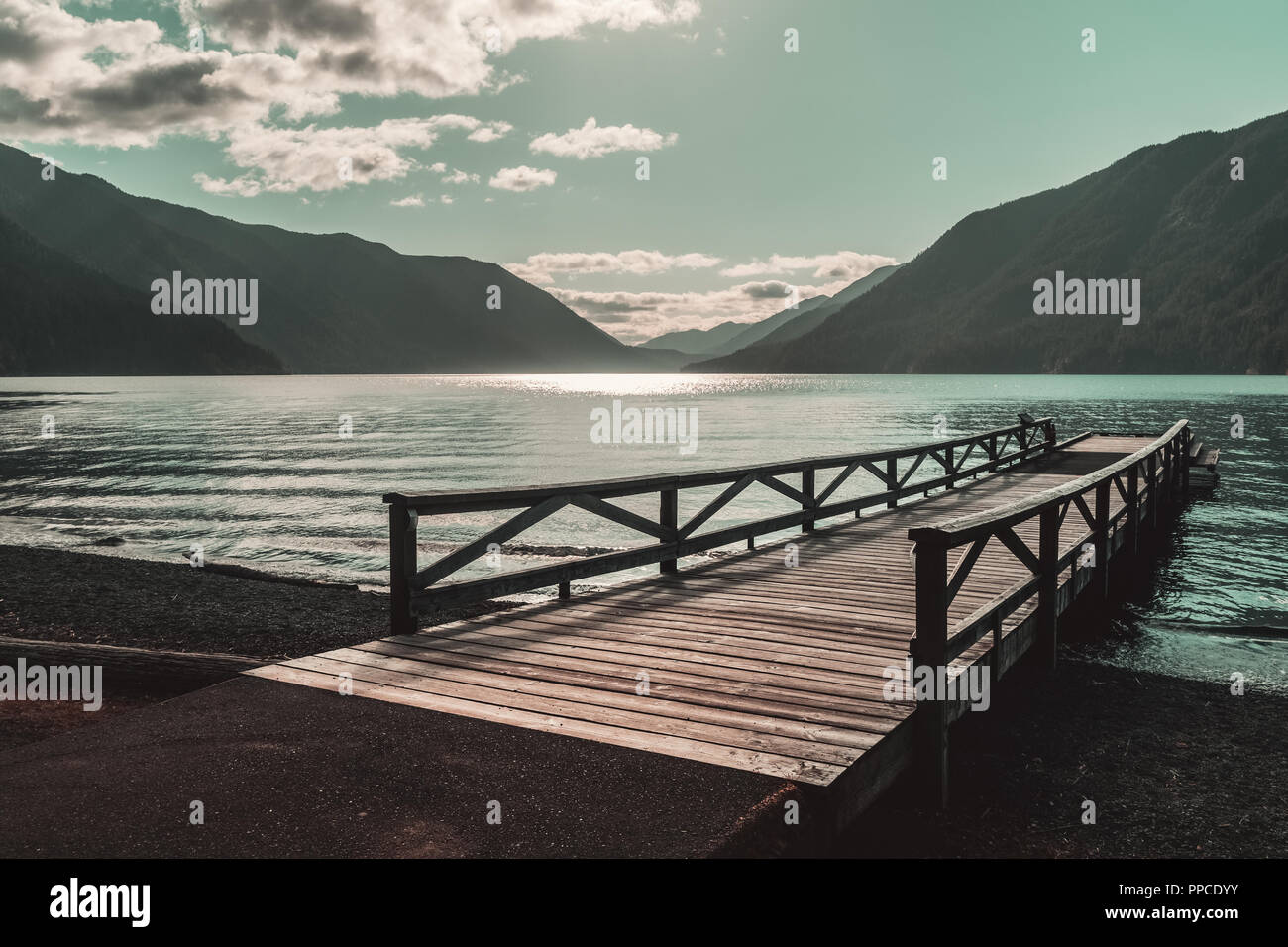Pontile in legno sul lago Crescent su un bellissimo e assolato pomeriggio con le montagne in distanza, il Parco Nazionale di Olympic, nello stato di Washington, USA. Foto Stock