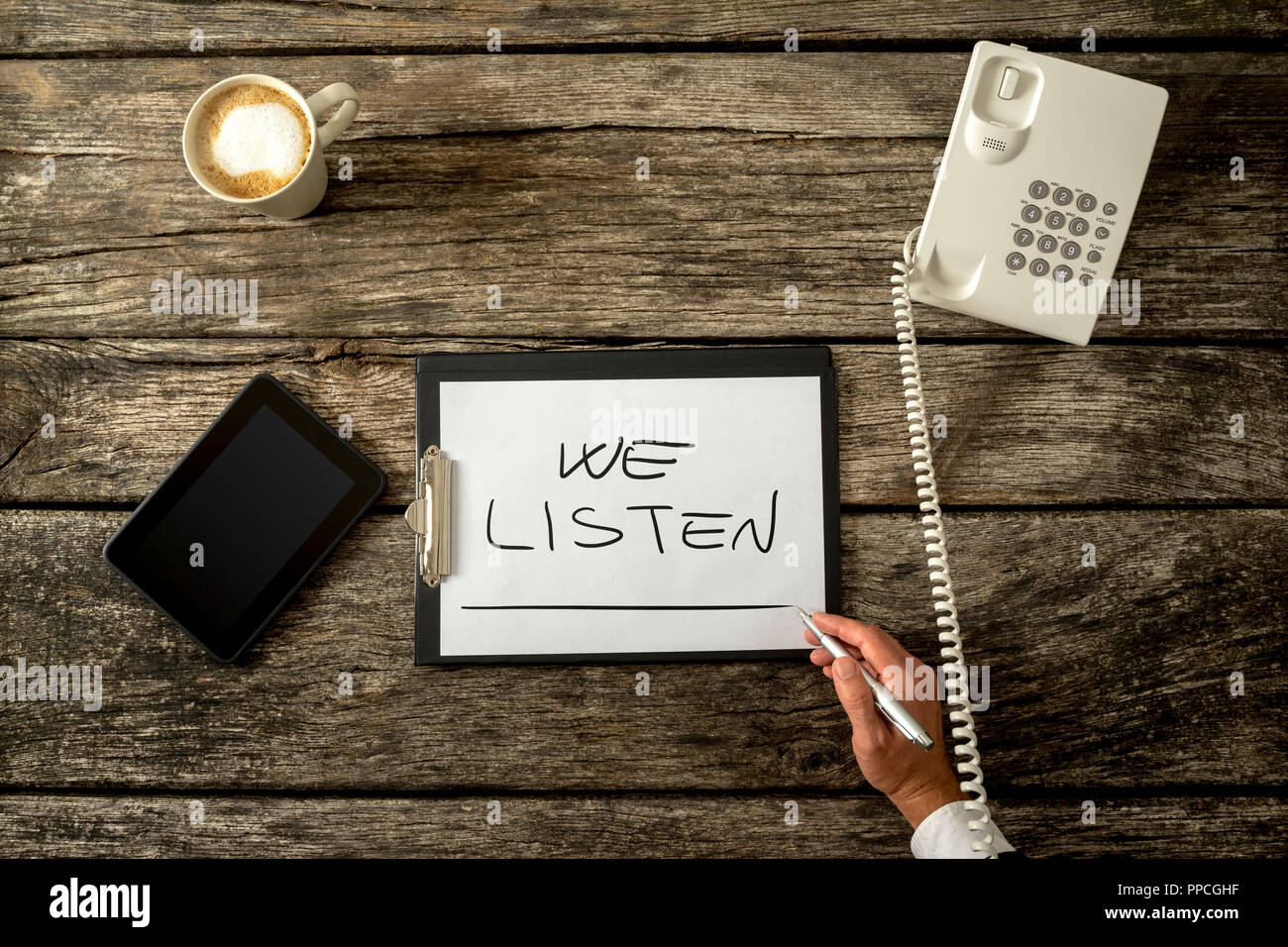 Sos telefono o helpline per persone in crisi personale - vista dall'alto di noi ascoltiamo segno sulla scrivania in legno con telefono digitale compressa e la tazza di caffè. Foto Stock