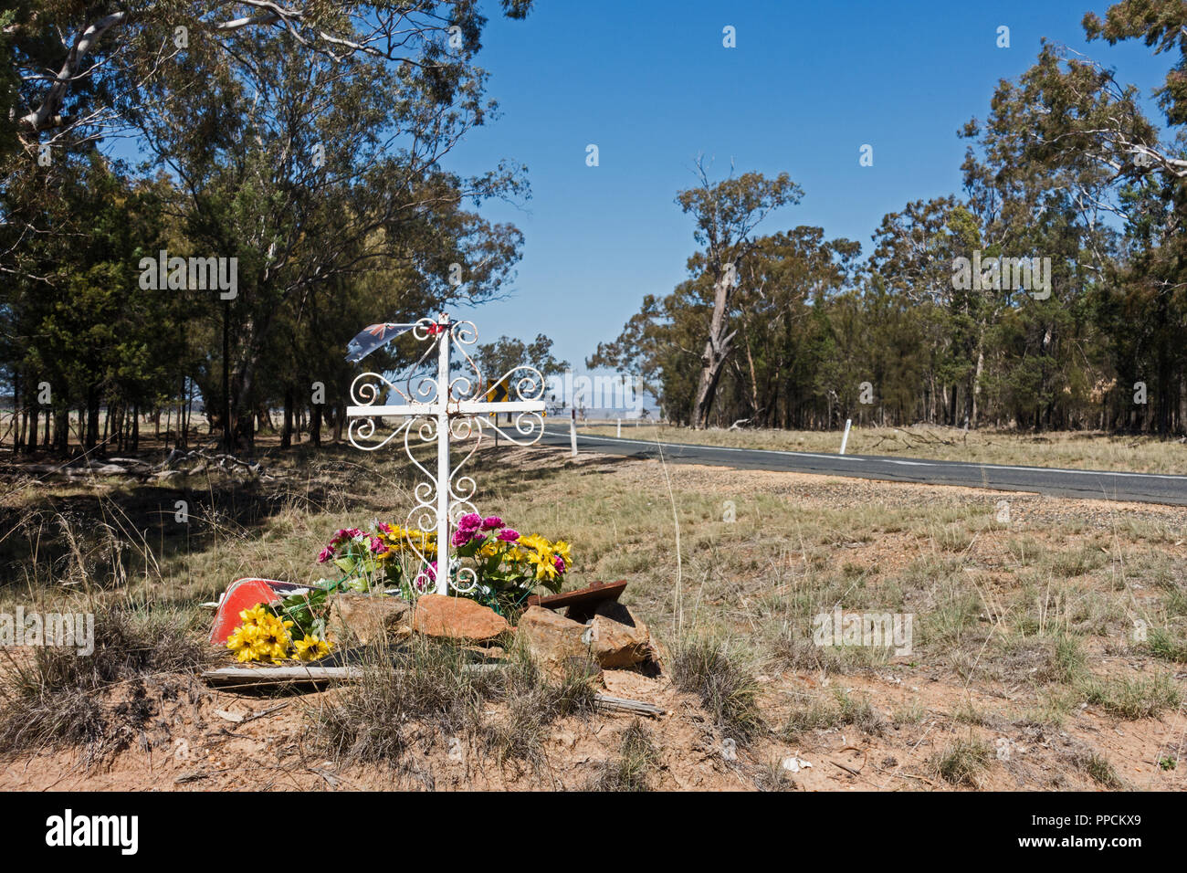 Memoriale sul ciglio della strada per la vittima di incidente con un elaborato una Croce Cristiana e fiori. Rural NSW Australia. Foto Stock