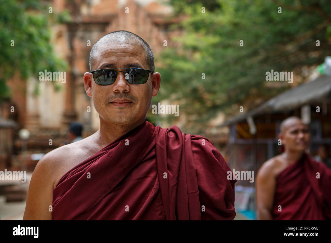 Testa e spalle ritratto di monaco buddista indossando occhiali da sole, Bagan, Mandalay Myanmar Foto Stock