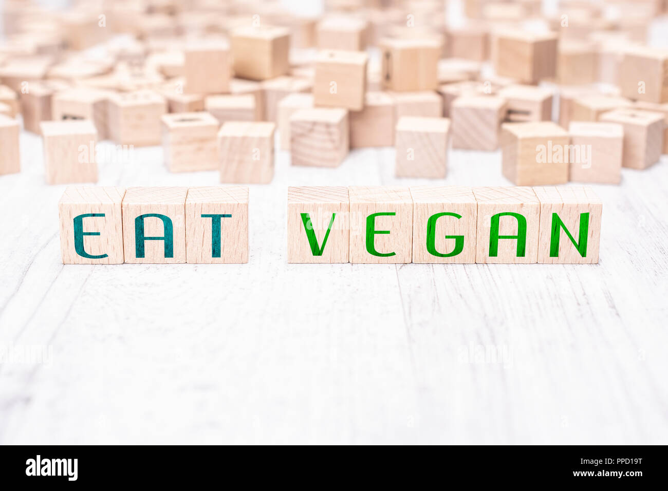 Le parole di mangiare Vegan formata da blocchi di legno su un tavolo bianco Foto Stock