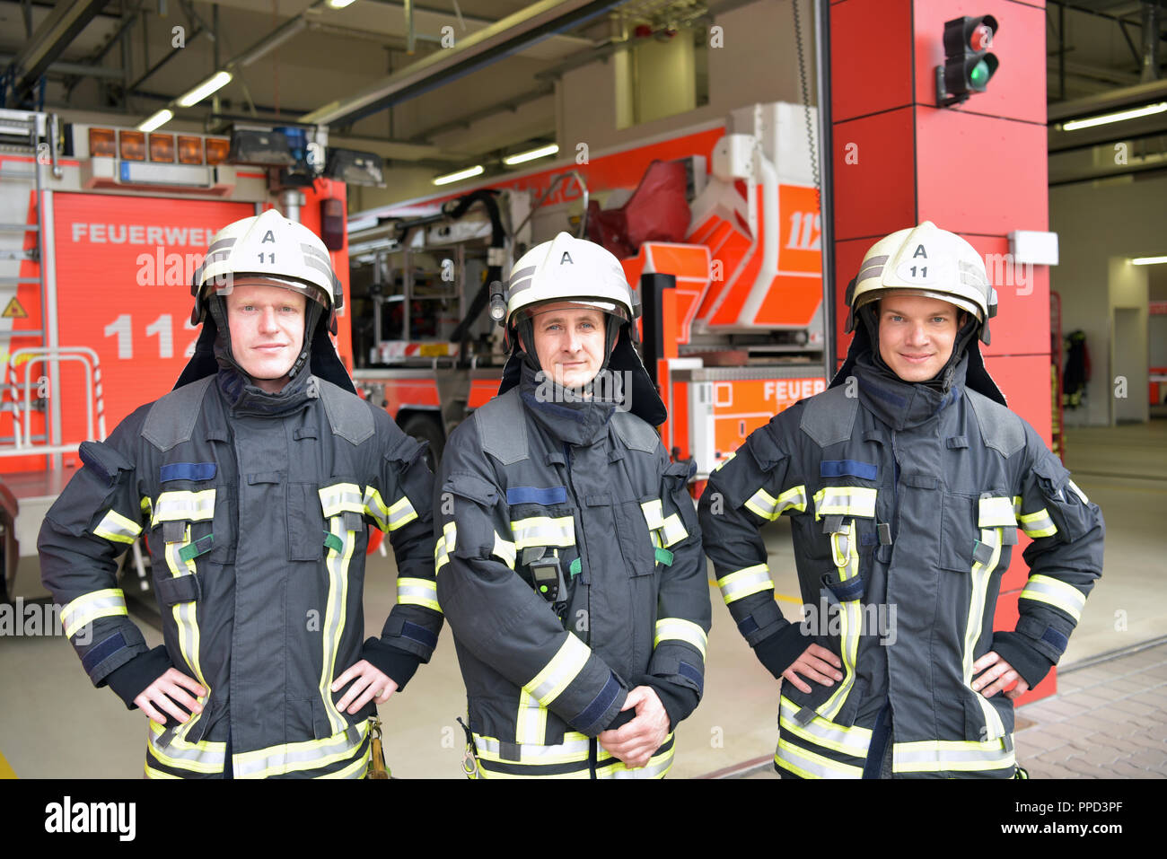 Gruppo di vigili del fuoco in corrispondenza del veicolo di emergenza nella stazione dei vigili del fuoco Foto Stock