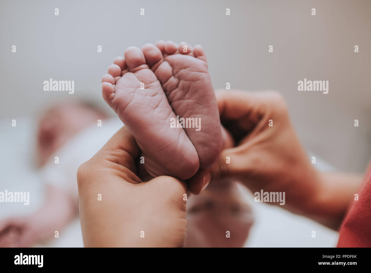 Madre tenendo in mano i piedi del neonato. Foto Stock
