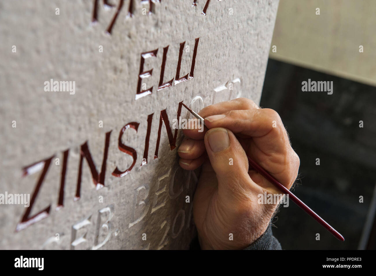 Un dipendente di 'Naturstein Halbich' dipinge le scritte su una tomba in pietra il negozio a Georg-Maisenbach-Strasse 2 a Perlacher Forst. La tradizionale a conduzione familiare stonemasonry business è stata attiva a Monaco di Baviera dal 1908 nelle aree della lapide Costruzione e restauro di pietra e fabbricazione di mobili. Foto Stock
