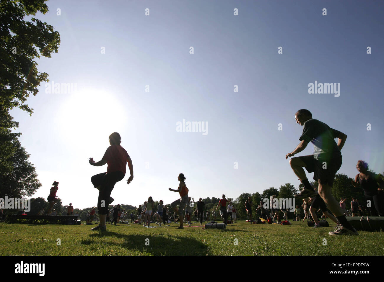 Gli atleti ricreativi muoversi sotto la guida di un istruttore presso la "palestra nel Parco", un programma di fitness della città di Monaco di Baviera, che si svolgono ogni giorno alle 18.00 orologio in parchi specifici a Monaco di Baviera. Foto Stock