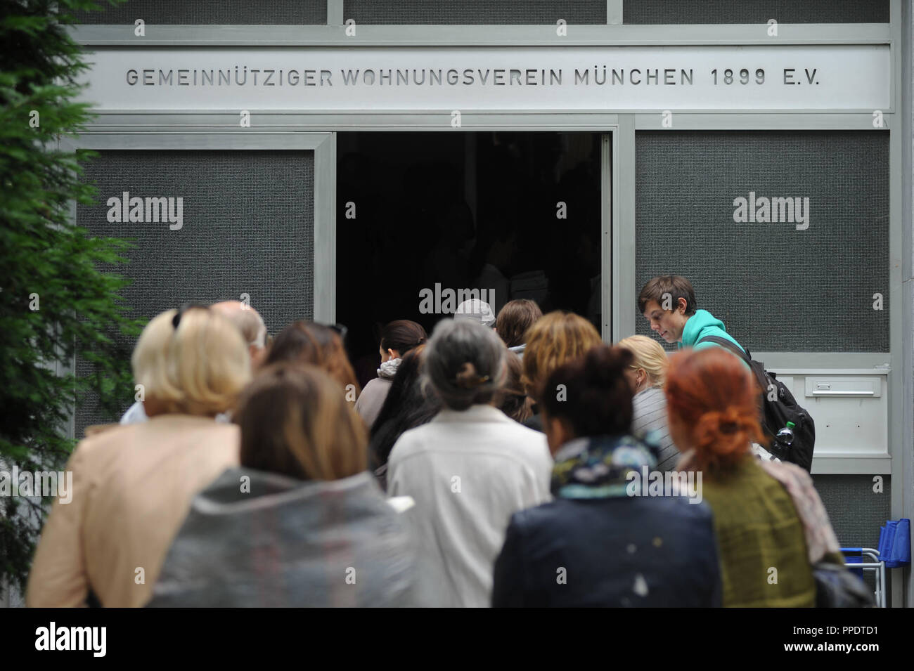 Una lunga coda di appartamento asilo stand alle 8.30 del mattino di fronte all'ufficio dell'associazione 'Gemeinnuetziger Wohnungsverein Muenchen 1899 e.V." nell'Parzivalstrasse 37 in Schwabing. L'attesa e i paesi non aderenti la speranza di registrarsi su un elenco delle parti interessate per appartamenti a prezzi accessibili. Foto Stock