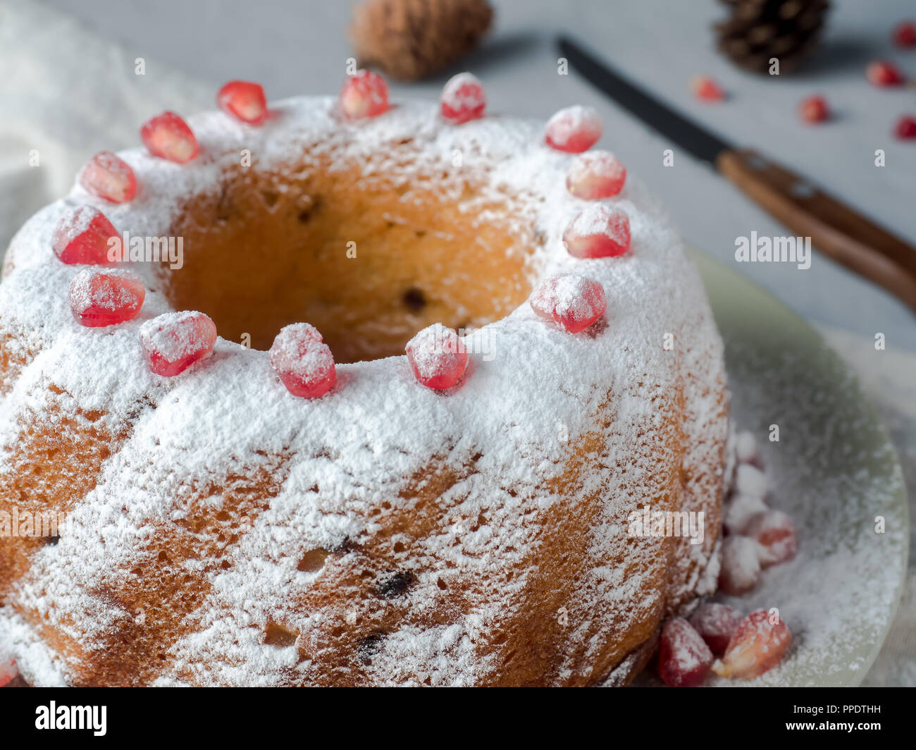 Torta di Natale in forma di una corona di fiori di zucchero in polvere e i semi di melograno su una piastra bianca Foto Stock