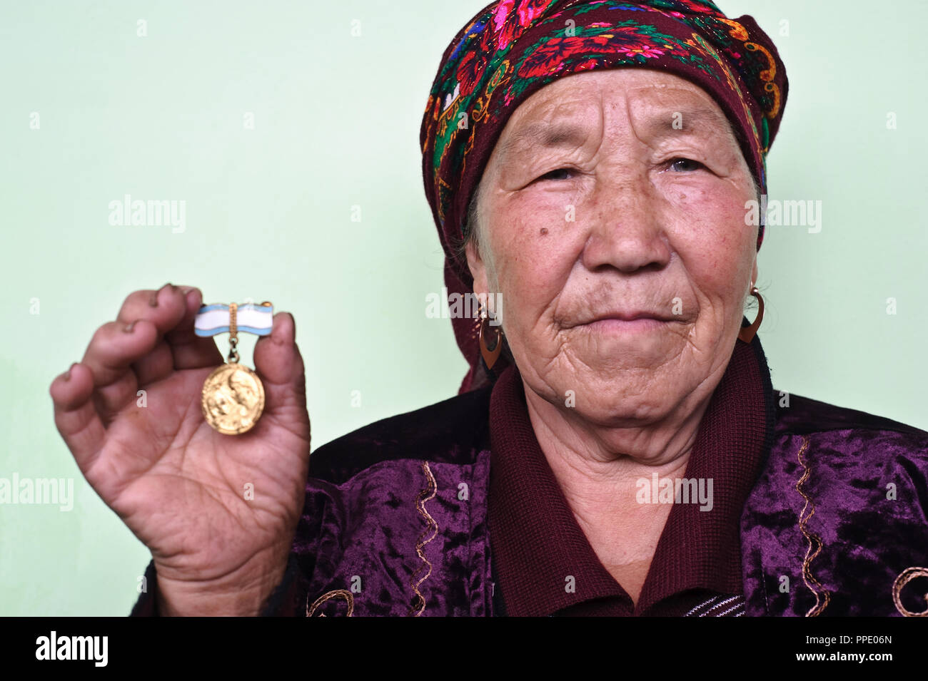 La donna che mostra una medaglia ha ottenuto per il parto per 5 bambini ( Kirghizistan). Come lei ha dato nascita a 10 bambini, ha ricevuto in totale 6 medaglie. Foto Stock