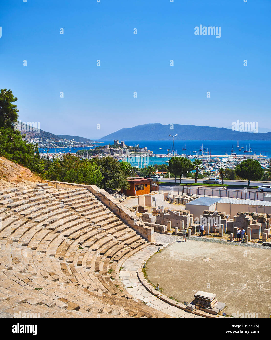 Bodrum, Turchia - Luglio 6, 2018. I turisti che visitano l'anfiteatro di Alicarnasso con Kumbahce bay e il Castello di San Pietro in background. Foto Stock