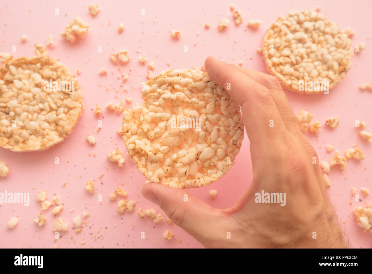 Torte di riso in mano maschio pastello su sfondo rosa, vista aerea Foto Stock