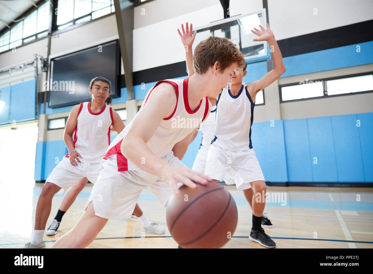 Maschio della High School della squadra di basket ball dribbling sulla corte Foto Stock