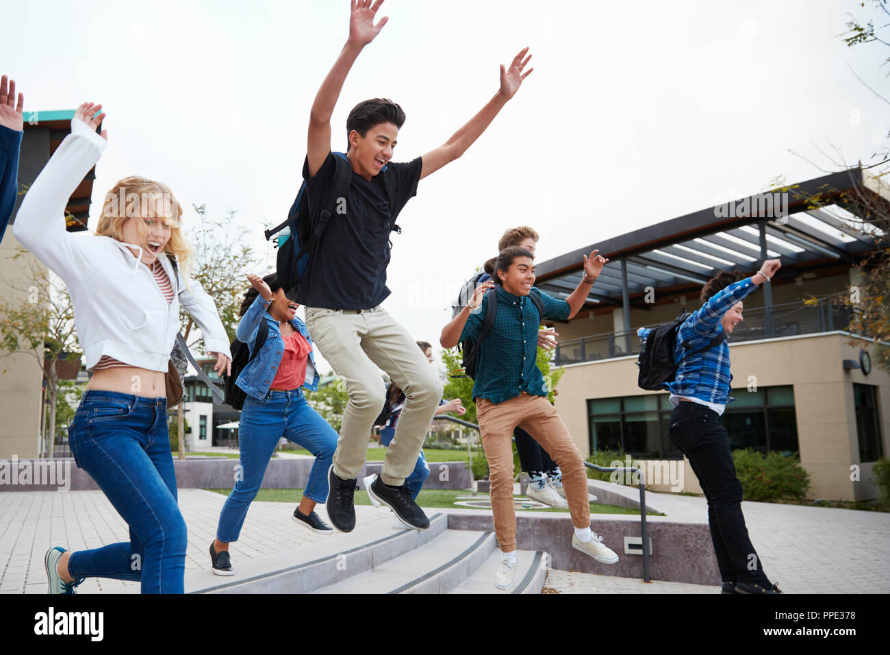 Un gruppo di studenti di scuola superiore i salti in aria al di fuori del College di edifici Foto Stock