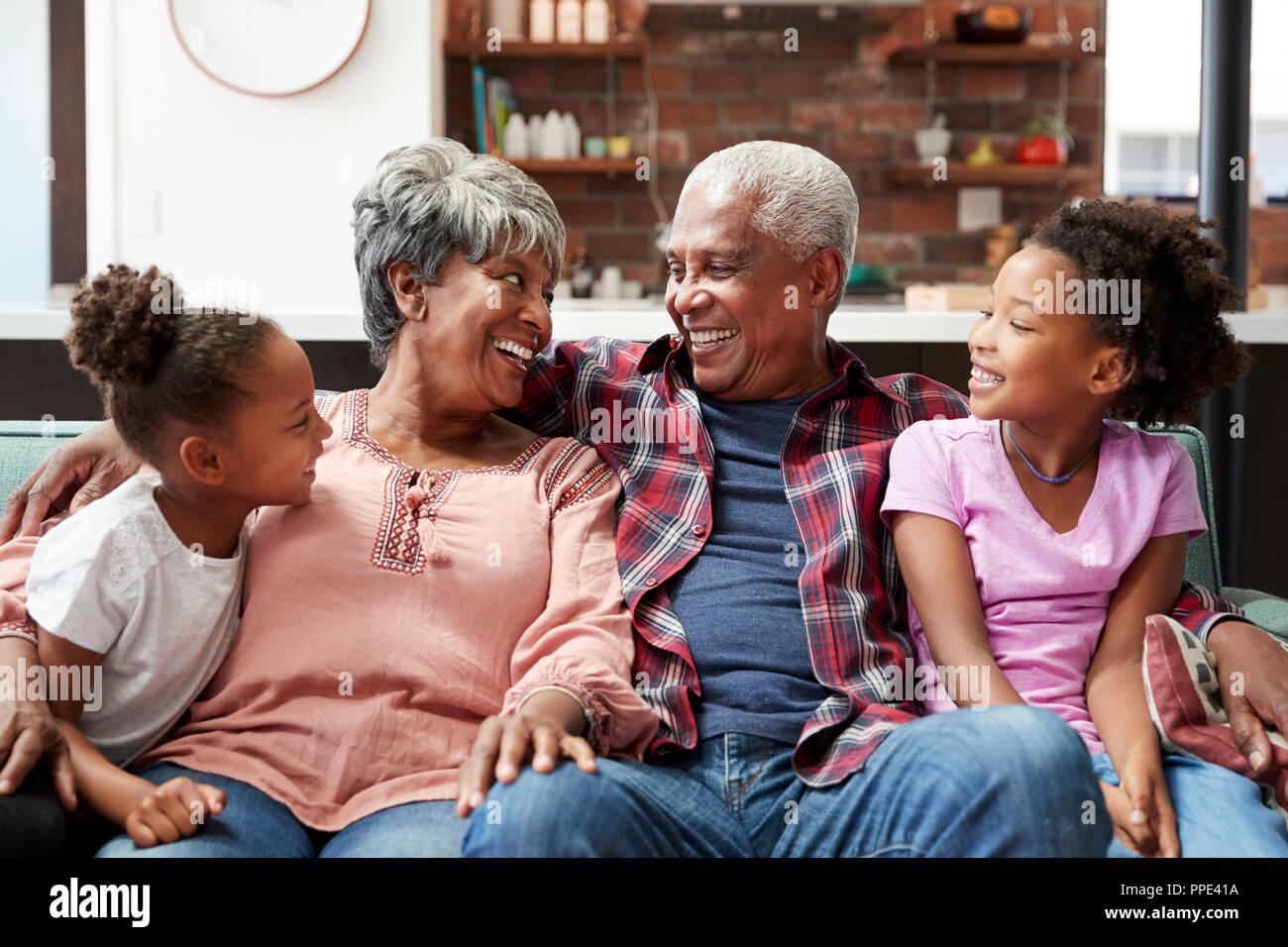 Nonni rilassante sul divano in casa con i nipoti Foto Stock